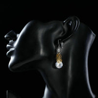 Side angle view of KHAISTA round dangling CZ drop earrings