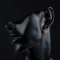 Side angle view of KHAISTA deep red round crystal clip earrings