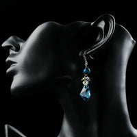Side angle view of KHAISTA sea blue crystal drop earrings