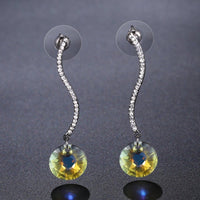 Side angle view of KHAISTA shiny arc long dangle drop earrings