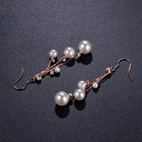 Close up of KHAISTA pearl chain dangle hook earrings