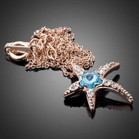 Side angle view of KHAISTA starfish blue crystal flower necklace