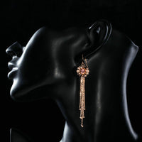 Close up of KHAISTA rose gold Stellux tassel drop earrings