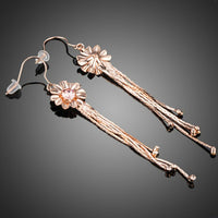 Side angle view of KHAISTA rose gold Stellux tassel drop earrings