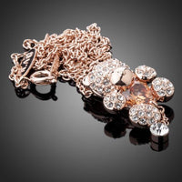 Side angle view of KHAISTA champagne crystal teddy bear necklace