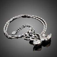Side angle view of KHAISTA white gold crystal goose necklace