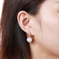 Side angle view of KHAISTA white pearl stud earrings